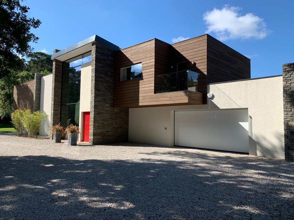 The entrance front, timber cladding, natural stone and full-height glazing